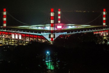 Rheinenergiestadion bei Nacht mit rot/weiß beleuchteten Pylonen